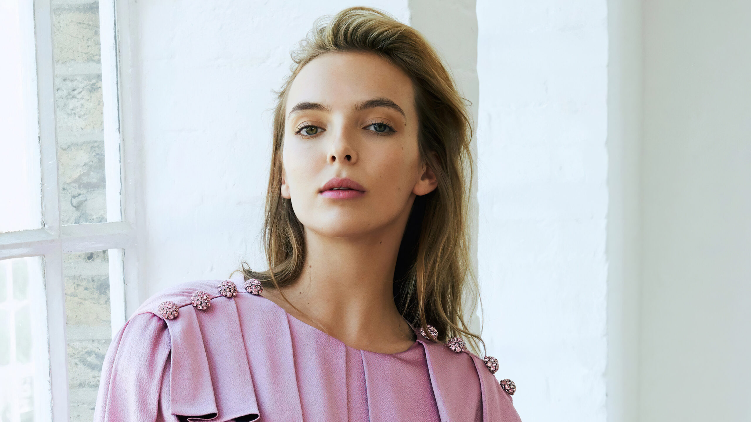 jodie_comer_is_wearing_light_pink_top_with_a_background_of_white_wall_4k_hd_celebrities